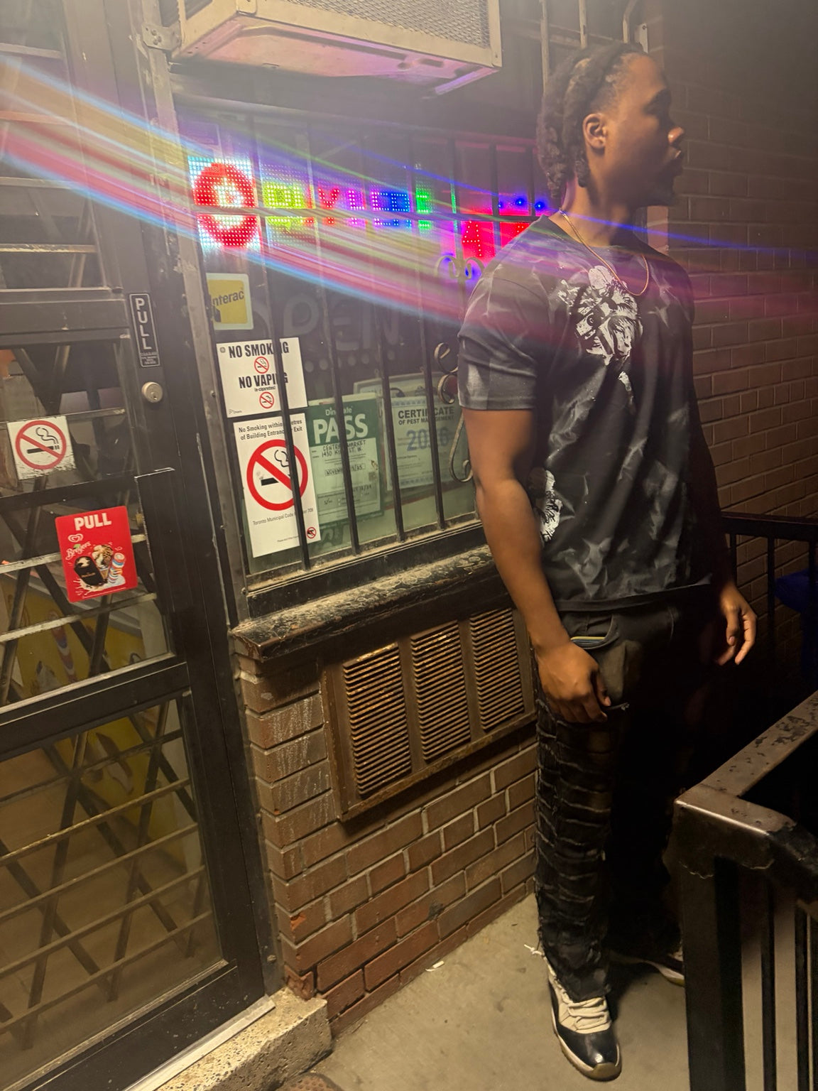 Model wearing Hold On Shadow Graphic Tee outside storefront at night